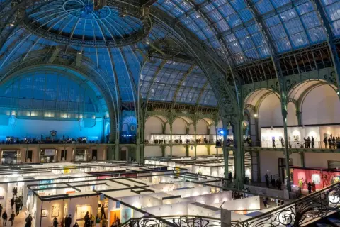 Vue intérieure du Grand Palais à Paris, une exposition d'art se déroule sous sa verrière spectaculaire.