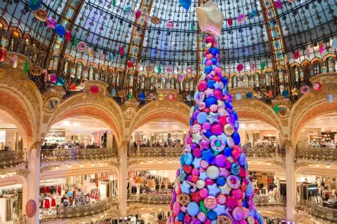 Arbre de Noël féerique fait de bonbons et étoiles, décorations colorées suspendues sous la coupole d'un grand magasin parisien.