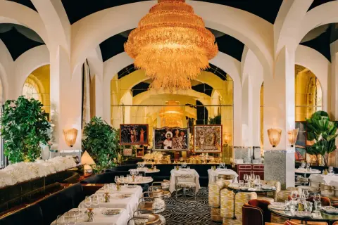 Un restaurant romantique à Paris, avec un lustre orange spectaculaire, des banquettes sombres, des tables dressées et des œuvres d'art.