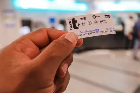 Main d'une personne tenant un ticket de métro parisien, prêt pour un voyage dans la ville.
