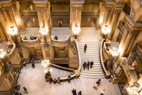 Vue aérienne de l'escalier monumental du Palais Garnier avec des visiteurs.
