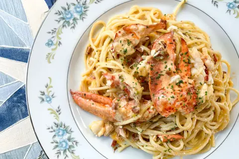 Délicieux spaghetti aux morceaux de homard, nappés d'une sauce crémeuse et parsemés de ciboulette. Un plat de pâtes au homard qui fait rêver.