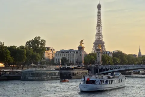 Une belle balade sur Seine à Paris, avec la Tour Eiffel et le pont Alexandre III en arrière-plan. Un bateau navigue paisiblement sur l'eau.