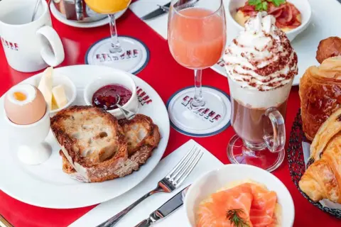 Un délicieux brunch avec enfants : toasts, œuf à la coque, confiture, jus d'orange, chocolat viennois et viennoiseries.