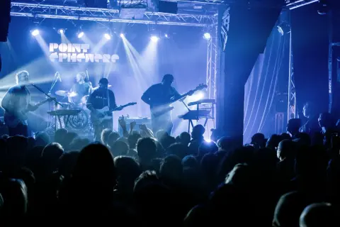 Un groupe joue sur scène sous des lumières bleues. Découvrez les **upcoming concerts in Paris** !