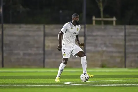 Joueur de football en action sur la pelouse du stade Charléty, concentré sur le ballon.
