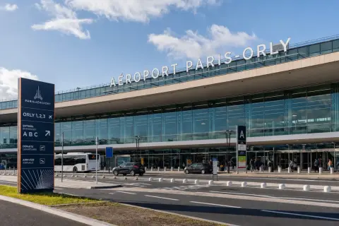 La navette Paris Orly attend devant l'aéroport. Panneaux indicateurs pour les entrées, départs et arrivées.