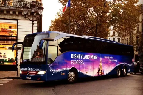 Un bus bleu "Disneyland Paris Express" circule dans Paris, prêt à emmener les visiteurs vers la magie.