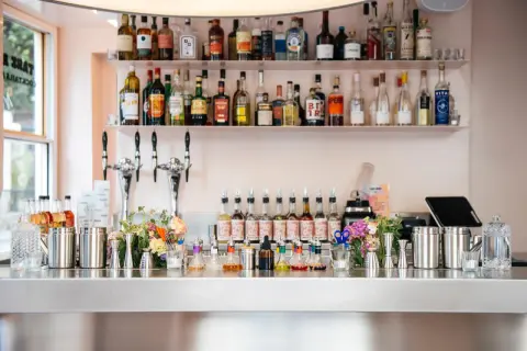Bar à cocktails prêt à servir, avec des bouteilles d'alcool sur les étagères et des sirops colorés sur le comptoir. Les "bisous bisous club reviews" sont excellentes pour ce bar !