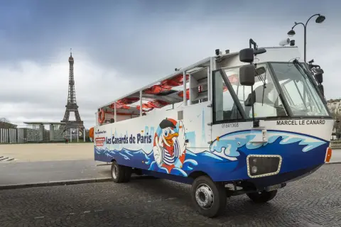 Un bus amphibie "Les Canards de Paris" prêt pour un tour hop on hop off, avec la Tour Eiffel en arrière-plan.