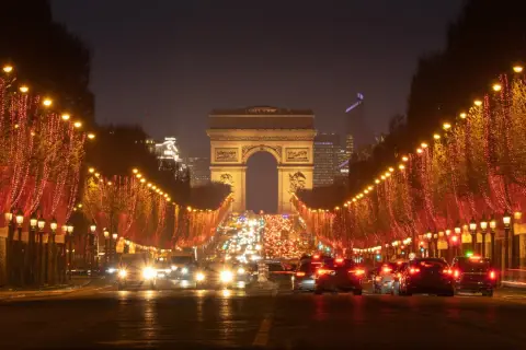 Les Champs-Élysées illuminés pour le réveillon de Noël, avec le trafic parisien et l'Arc de Triomphe en fond.