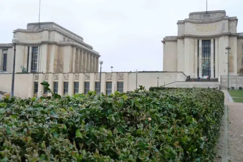 Le **Palais de Chaillot** à Paris, avec ses deux ailes symétriques et sa végétation luxuriante au premier plan.