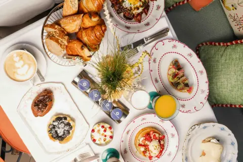 Un plateau de viennoiseries, tartes, œufs, jus et café pour un meilleur brunch parisien.
