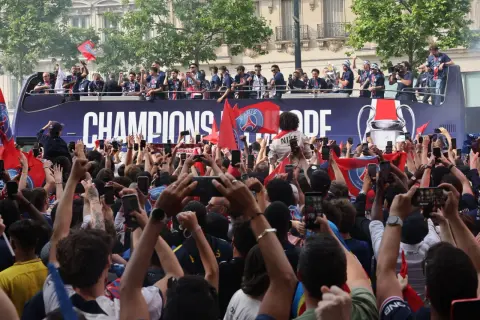 Foule en liesse à Paris, le 14 juillet, pour célébrer les champions sur un bus à impériale. Les téléphones sont levés pour immortaliser l'instant.