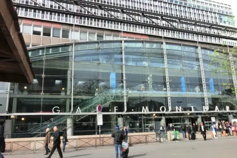 La gare de Montparnasse, avec sa façade de verre moderne, accueille des voyageurs pressés.
