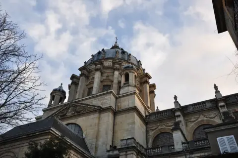 Dôme majestueux de l'église du Val-de-Grâce, se détachant sur un ciel nuageux. L'architecture baroque est impressionnante.
