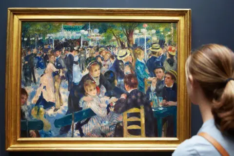 Une femme admire une peinture de Renoir représentant une scène animée de danseurs et de convives dans un jardin.