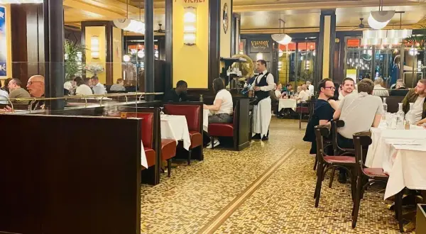 Ambiance chaleureuse dans un bouillon République, avec ses banquettes rouges, ses tables dressées et ses clients attablés.