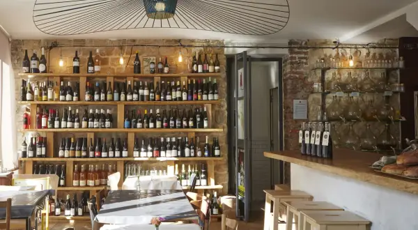 Ambiance chaleureuse dans la cave à manger, avec des étagères remplies de bouteilles de vin, des tables dressées et un bar en bois.