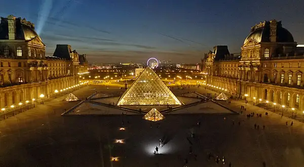 La Pyramide du Louvre illuminée, une belle soirée du 14 juillet. La foule admire le spectacle nocturne.