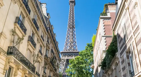 La Tour Eiffel se dresse entre des immeubles parisiens. Un aperçu parfait pour un paris visite pass.