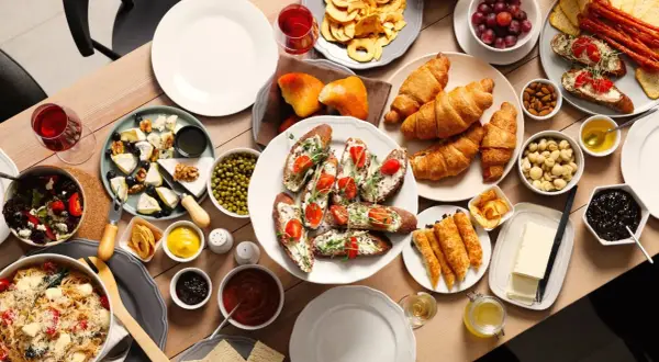 Un délicieux brunch en famille avec croissants, toasts garnis, fromages, fruits et pâtes.
