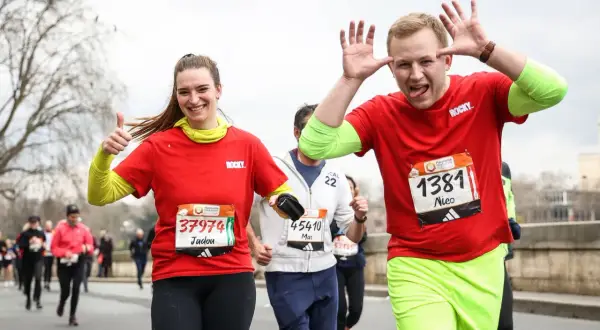 Joyeux coureurs au semi-marathon Paris 2026, une femme fait un pouce levé, un homme fait des grimaces.
