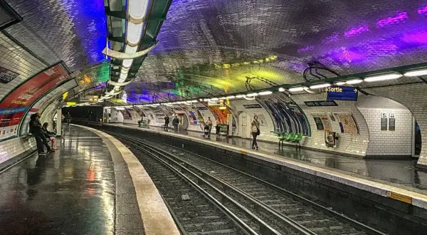 Le quai du métro Arts et Métiers, illuminé par des lumières colorées rappelant un atelier des lumières, attend les voyageurs.