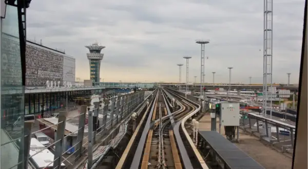 Vue depuis le train automatique Orlyval, avec la tour de contrôle et les voies ferrées. On imagine un voyage vers la Tour Eiffel.