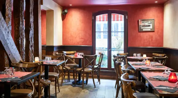 Ambiance chaleureuse au restaurant Le Molière, avec ses tables dressées, ses bougies et ses poutres apparentes.