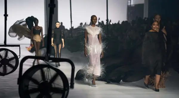 Mannequins défilent sur un podium, une robe ornée de plumes, un aperçu de la Paris Fashion Week 2026.