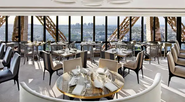 Un restaurant cool pour ado avec vue panoramique sur Paris. Tables dressées, sièges confortables, ambiance chic.