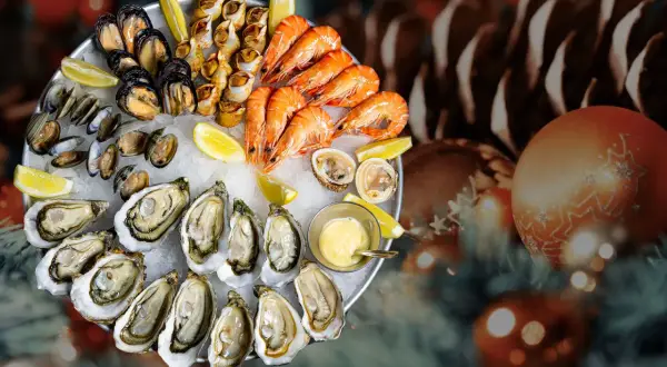 Plateau de fruits de mer frais, une tradition de Noël en France, avec huîtres, crevettes, moules et bigorneaux, sur un lit de glace, décoré de citrons et d'une sauce.