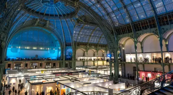 Vue intérieure du Grand Palais à Paris, une exposition d'art se déroule sous sa verrière spectaculaire.