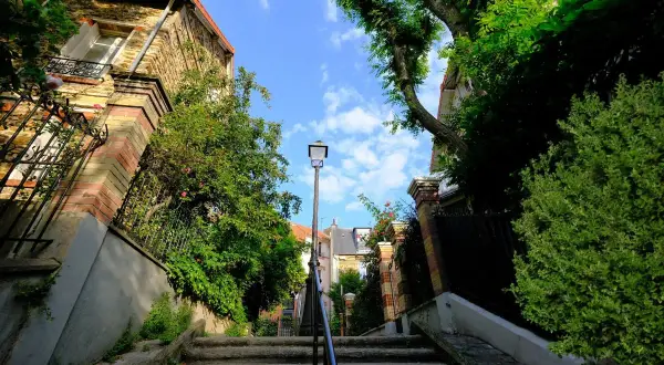 Escalier verdoyant à Paris, une invitation à une activité insolite loin des foules. Un chemin secret sous le ciel bleu.