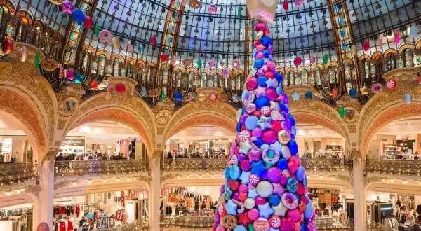 Arbre de Noël féerique fait de bonbons et étoiles, décorations colorées suspendues sous la coupole d'un grand magasin parisien.