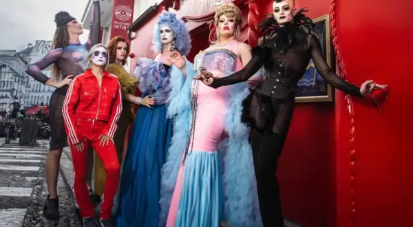 Cinq artistes de drag queen posent devant le cabaret Madame Arthur à Paris, prêts pour un spectacle flamboyant.