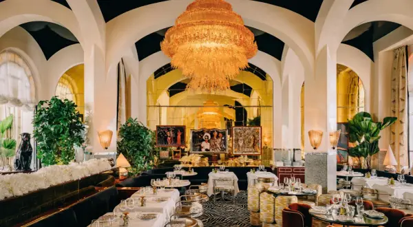 Un restaurant romantique à Paris, avec un lustre orange spectaculaire, des banquettes sombres, des tables dressées et des œuvres d'art.