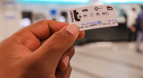 Main d'une personne tenant un ticket de métro parisien, prêt pour un voyage dans la ville.