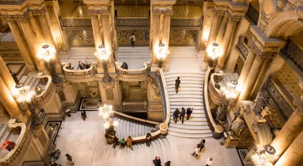 Vue aérienne de l'escalier monumental du Palais Garnier avec des visiteurs.