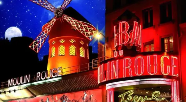 Le Moulin Rouge illuminé la nuit, avec son moulin rouge emblématique et ses néons. Le prix d'entrée pour ce spectacle légendaire est une invitation à la féerie.