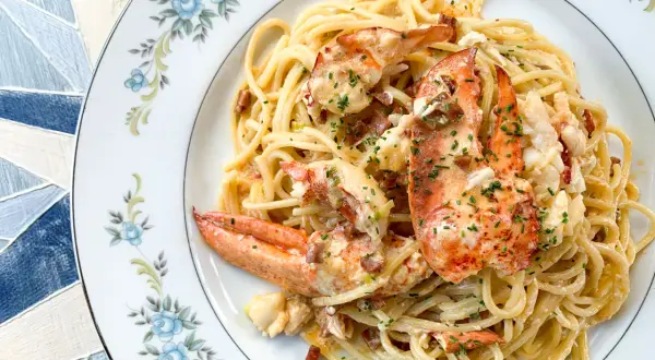 Délicieux spaghetti aux morceaux de homard, nappés d'une sauce crémeuse et parsemés de ciboulette. Un plat de pâtes au homard qui fait rêver.
