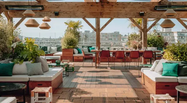 Le perchoir Ménilmontant, un rooftop chic avec vue sur Paris. Canapés confortables, tables dressées, végétation luxuriante et ambiance estivale.