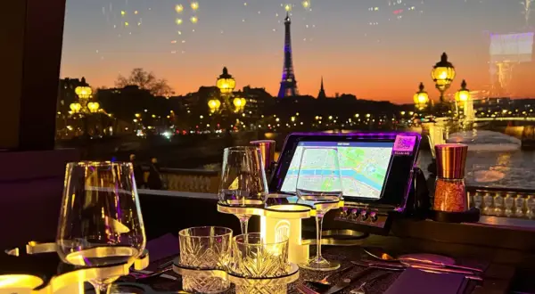Vue sur Paris au crépuscule, avec la Tour Eiffel illuminée. Une table dressée pour un dîner romantique, parfaite pour savoir où manger après minuit.