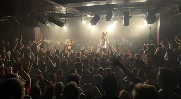 Foule en délire dans une salle de concert, le nombre de places semble limité mais l'ambiance est électrique.