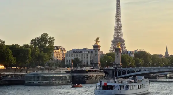 Une belle balade sur Seine à Paris, avec la Tour Eiffel et le pont Alexandre III en arrière-plan. Un bateau navigue paisiblement sur l'eau.
