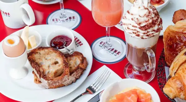 Un délicieux brunch avec enfants : toasts, œuf à la coque, confiture, jus d'orange, chocolat viennois et viennoiseries.