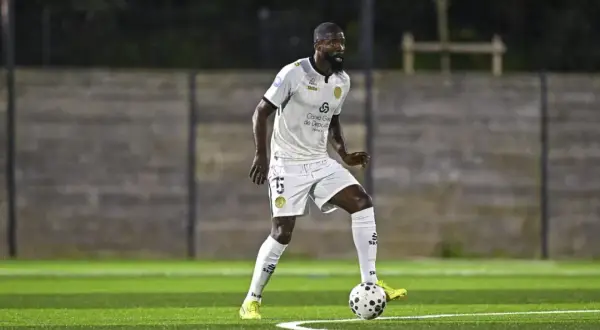 Joueur de football en action sur la pelouse du stade Charléty, concentré sur le ballon.