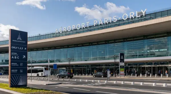 La navette Paris Orly attend devant l'aéroport. Panneaux indicateurs pour les entrées, départs et arrivées.