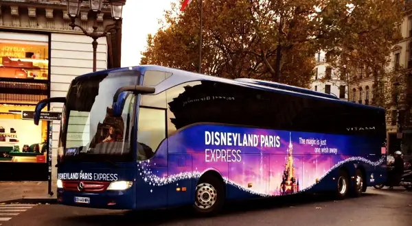 Un bus bleu "Disneyland Paris Express" circule dans Paris, prêt à emmener les visiteurs vers la magie.